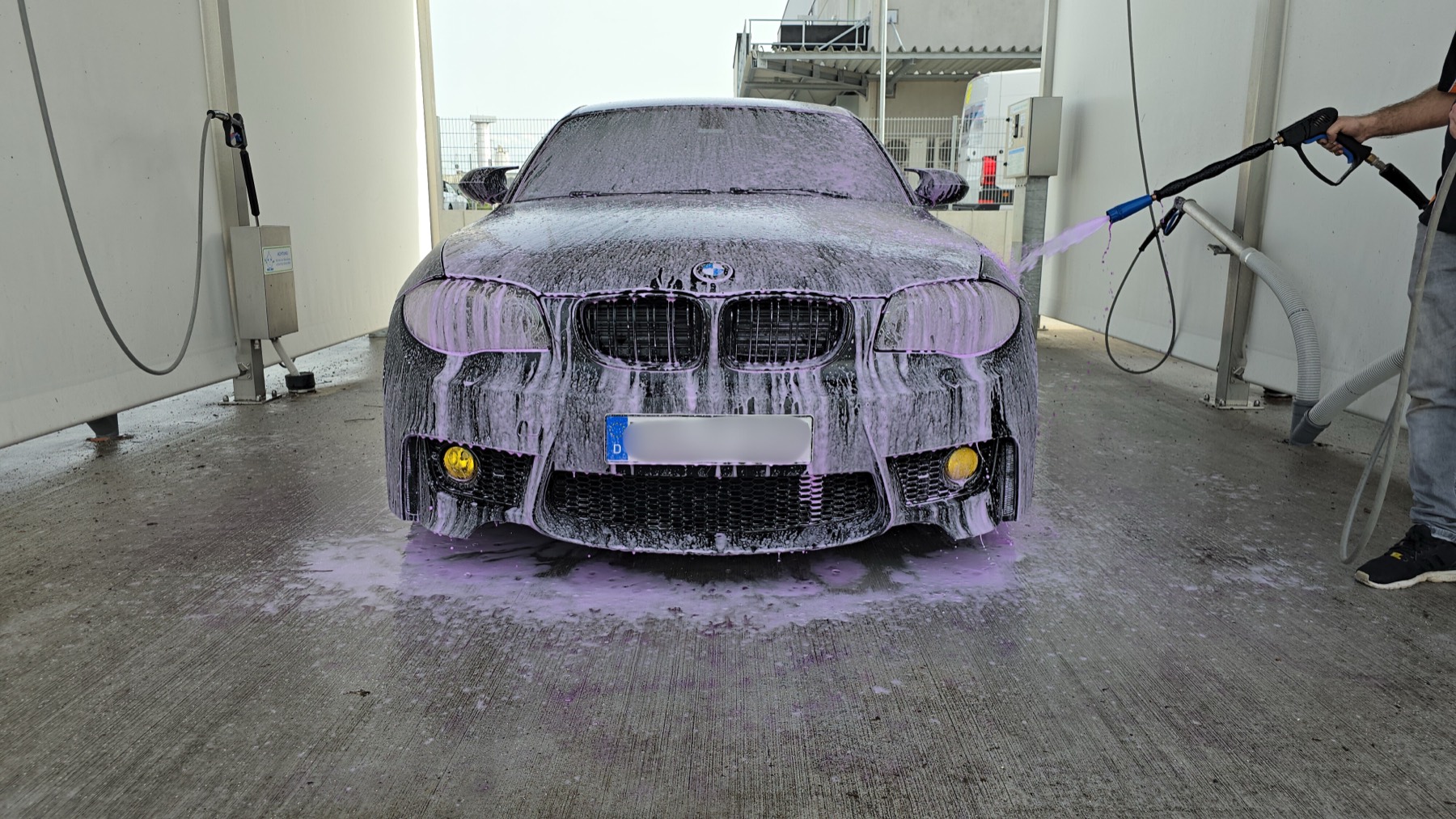 Ein Auto wird in der Waschbox mit dichtem Intensivschaum aus der Schaumkanone eingesprüht